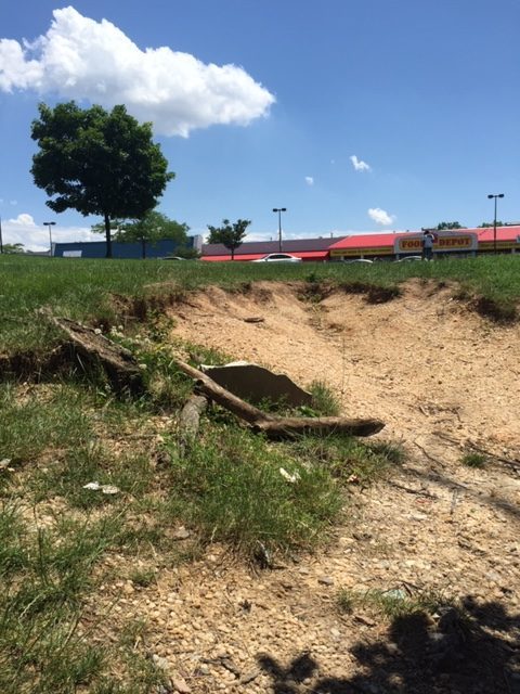 Soil erosion at the Belair Edison Crossing Shopping Center has exposed portion of a grave marker from the old Laurel Cemetery.